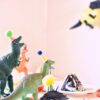 assorted-color dinosaur toys near slice cake on white table